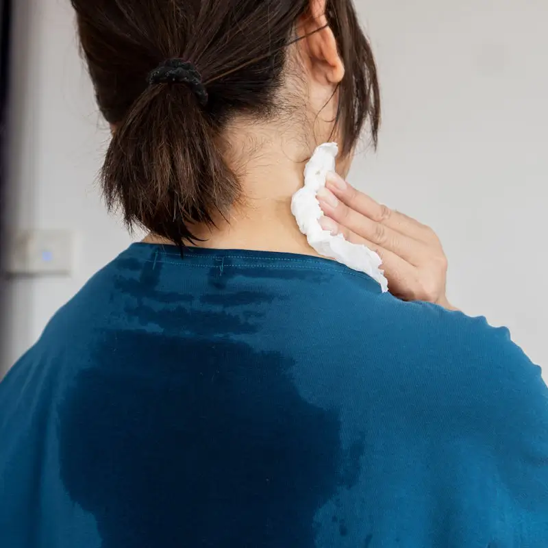 Frau mit deutlich sichtbarem Schweißfleck unter der Achsel – typisches Symptom bei Hyperhidrose